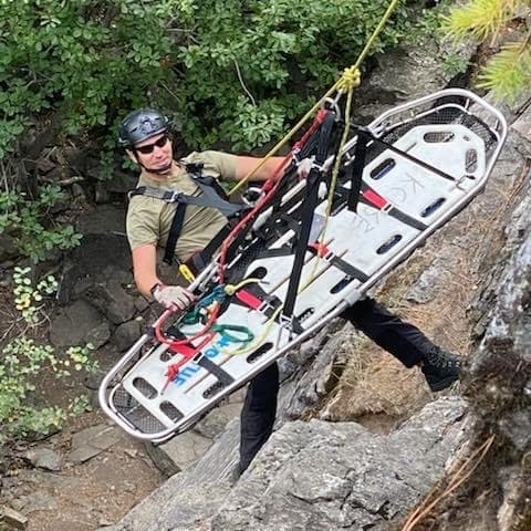 Instructor lowering a rescue litter on a technical rope system